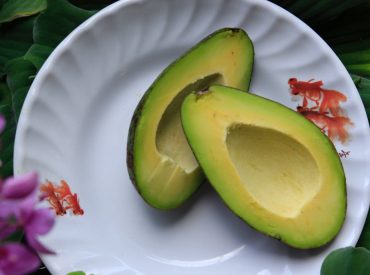 Avocado sliced in half on a plate to show an example of a healthy fat