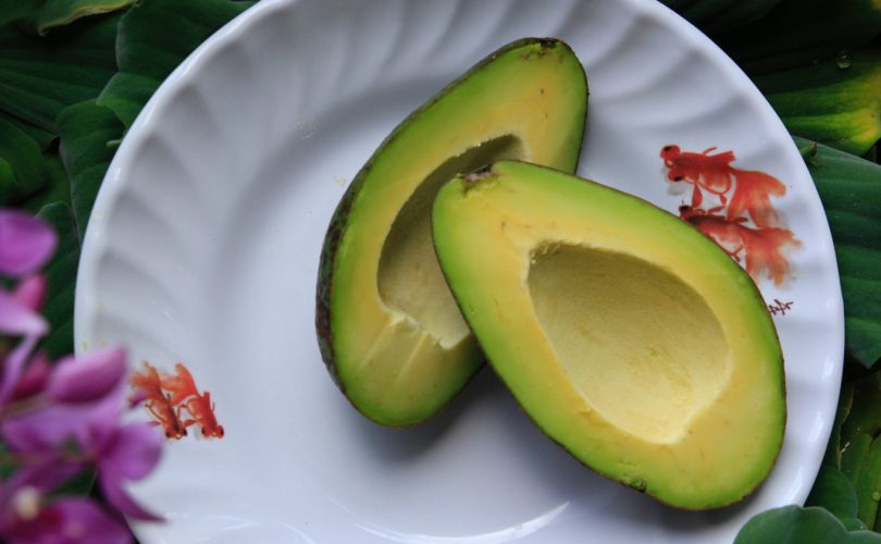 Avocado sliced in half on a plate to show an example of a healthy fat