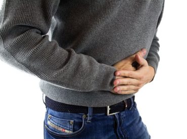 Man with his hands on his stomach because he has indigestion has indigestion and problems with gut health