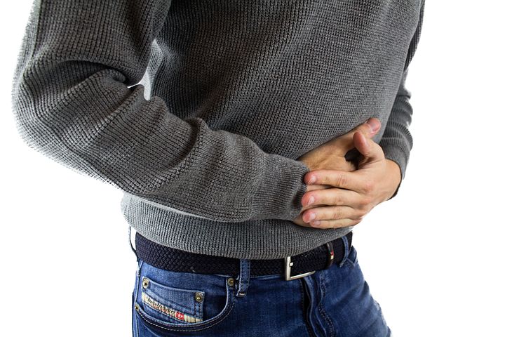 Man with his hands on his stomach because he has indigestion has indigestion and problems with gut health