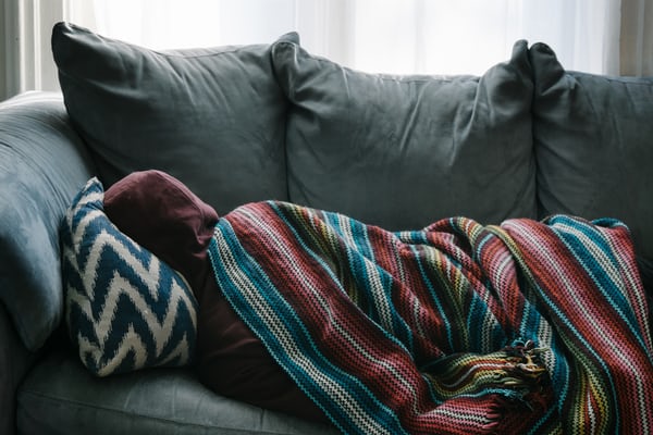 person laying on couch with blanket